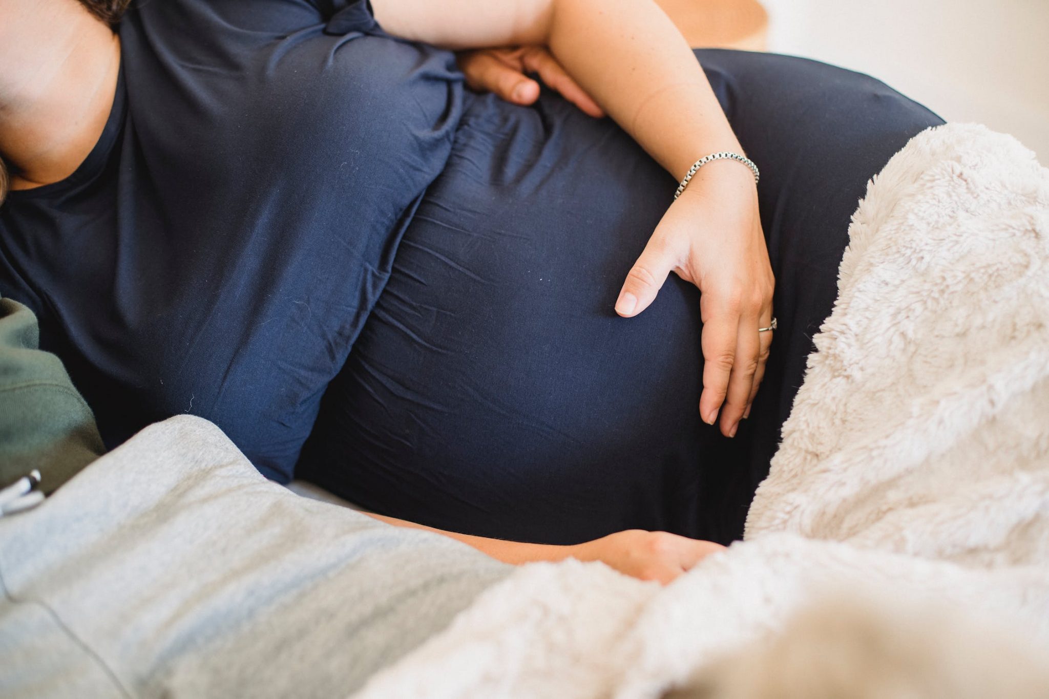 Zwangere vrouw slaapt comfortabel met een zwangerschapskussen ter ondersteuning van buik en rug