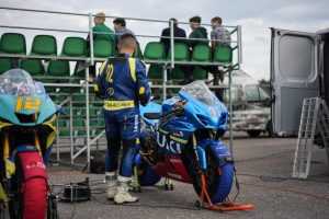 Home Motorrijder in rood eendelig motorpak op racetrack - voorbeeld van beste motorpak voor circuitgebruik